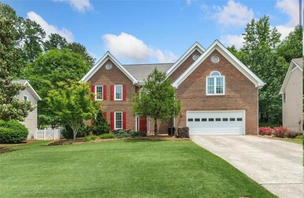 View of front of home featuring brick siding, driveway, a front lawn, and a garage
