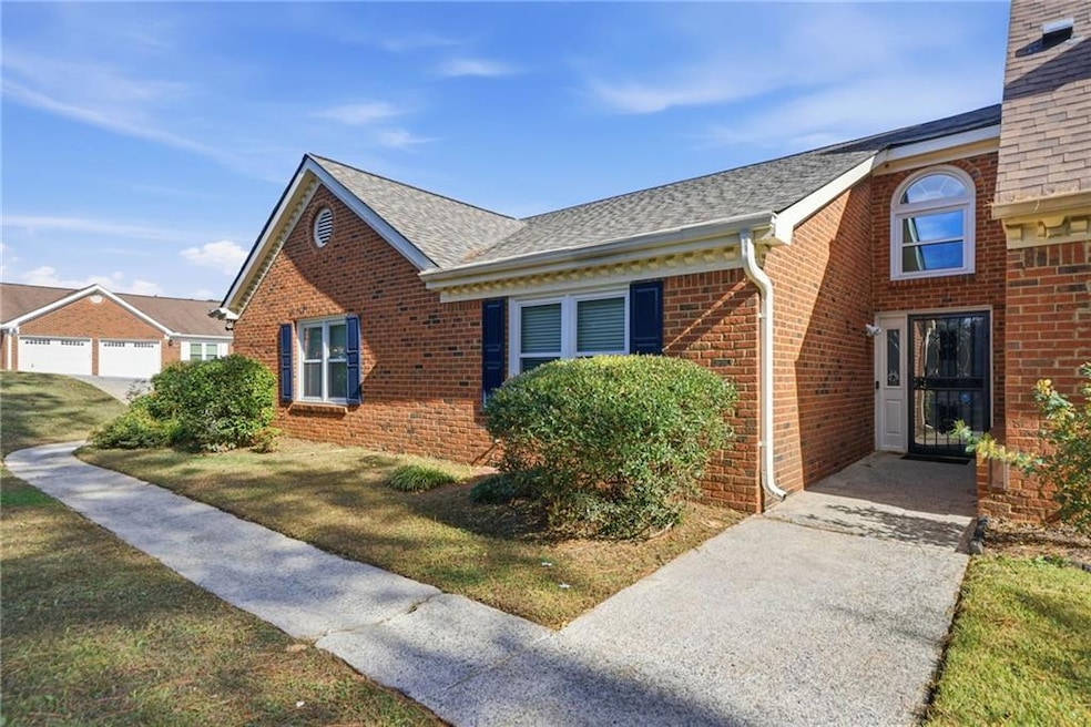 View of front facade with roof with shingles, brick siding, and a front yard
