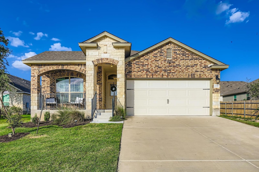 French country inspired facade featuring brick siding, an attached garage, driveway, stone siding, and roof with shingles