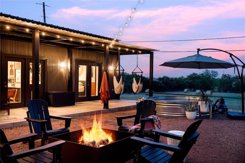 Patio terrace at dusk featuring a hot tub, a patio area, and an outdoor fire pit