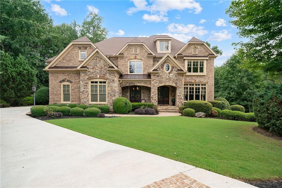View of front facade with a front yard, a porch, brick siding, stone siding, and a shingled roof