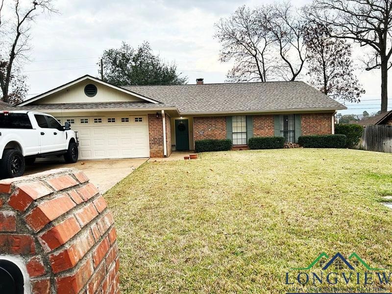 Single story home featuring an attached garage, brick siding, concrete driveway, and a shingled roof