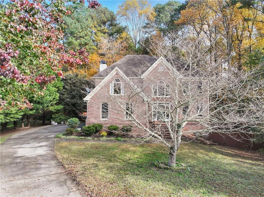 View of front of property with a chimney, brick siding, a front yard, and asphalt driveway