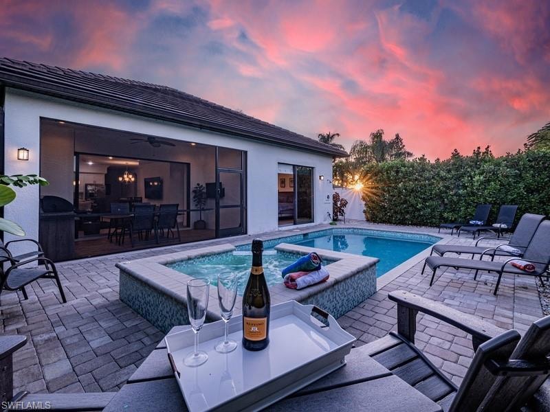 Pool at dusk with a patio and ceiling fan