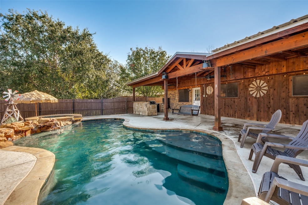 View of HEATED swimming pool featuring area for grilling, a patio, a pool with connected hot tub, and a fenced backyard