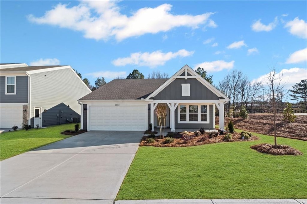 View of front of property with an attached garage, a front lawn, concrete driveway, and board and batten siding