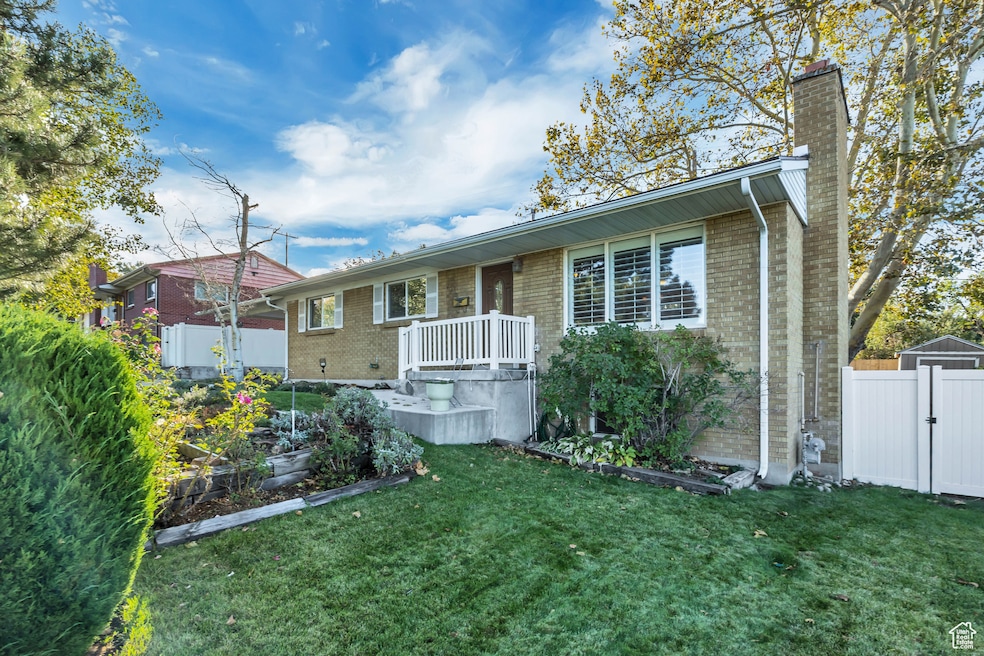 Single story home featuring a garden, brick siding, a chimney, and a gate