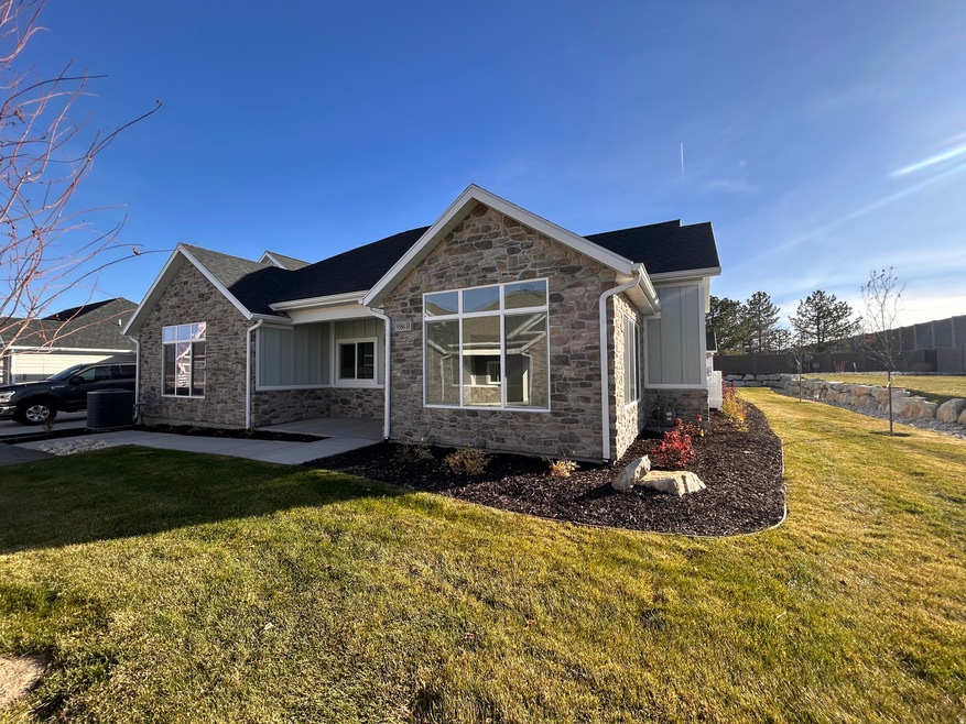 Rear view of house featuring stone siding, a yard, board and batten siding, and covered porch