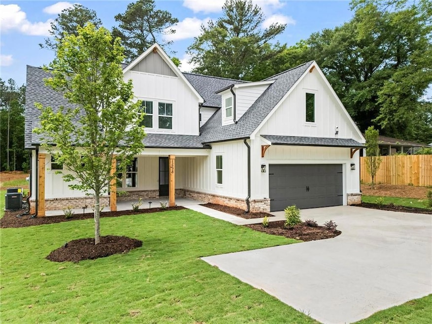 Modern farmhouse with a shingled roof, central AC unit, driveway, board and batten siding, and covered porch