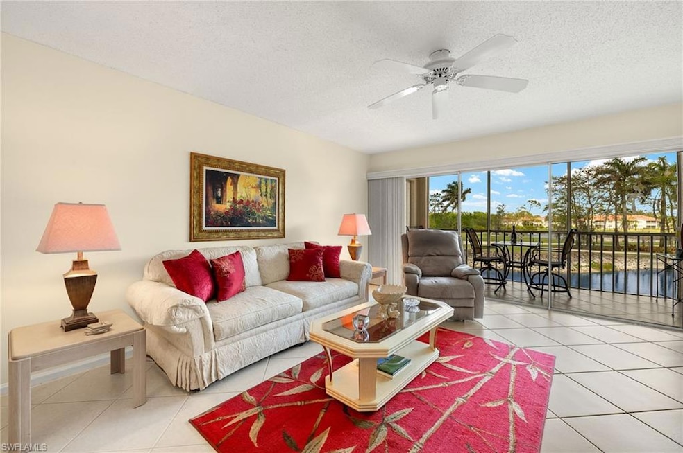 Living room featuring a textured ceiling, light tile patterned floors, and a ceiling fan