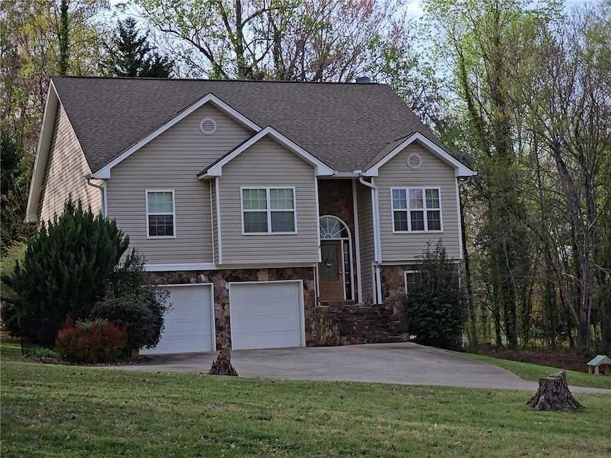 Bi-level home featuring an attached garage, stone 
