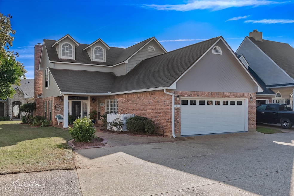 Traditional home featuring a front yard, driveway, brick siding, a shingled roof, and an attached garage