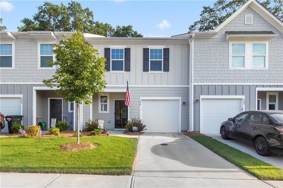 Townhome / multi-family property featuring concrete driveway, board and batten siding, a garage, and a front lawn