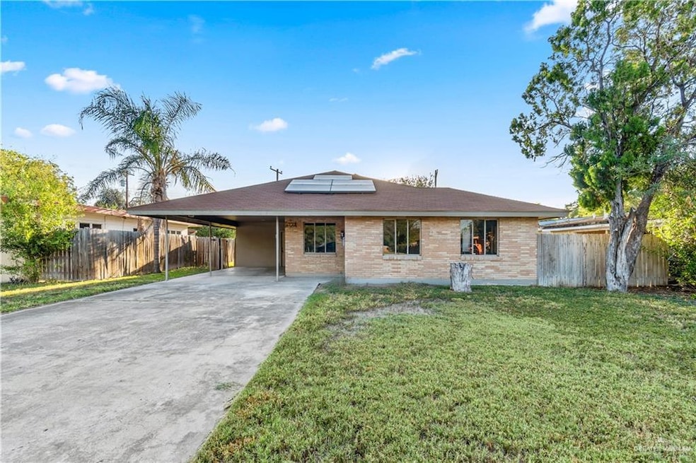 Ranch-style house with roof mounted solar panels, brick siding, driveway, an attached carport, and a patio