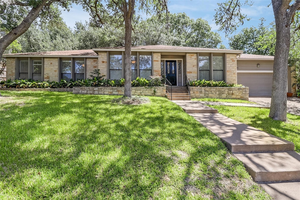 Mid-century home featuring stone siding, a garage, a front lawn, and roof with shingles