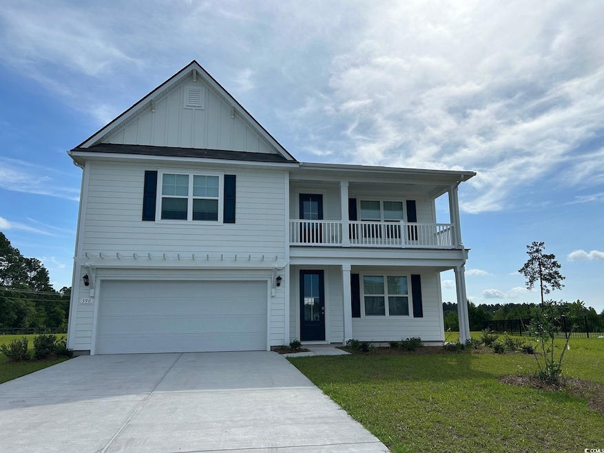 View of front of home with board and batten siding, a balcony, a front lawn, driveway, and an attached garage