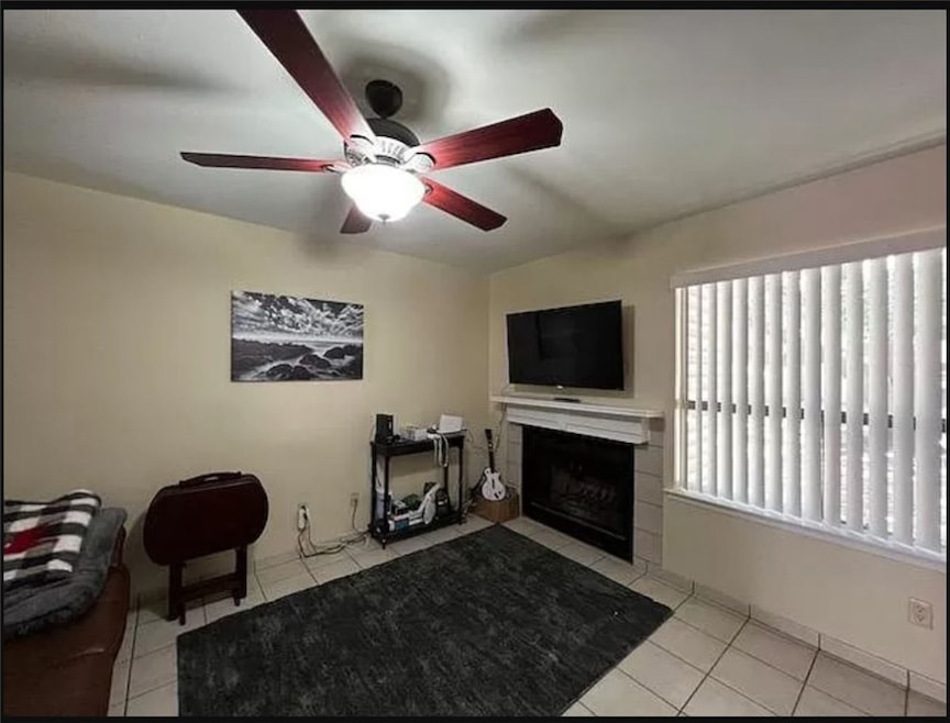 Living area with a ceiling fan, a tile fireplace,