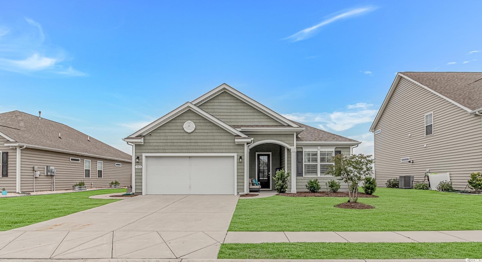 View of front of home featuring concrete driveway, a front yard, cooling unit, and an attached garage