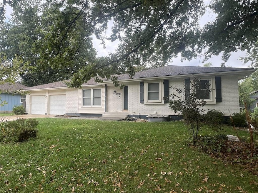 Ranch-style home featuring brick siding, a front lawn, an attached garage, concrete driveway, and a shingled roof