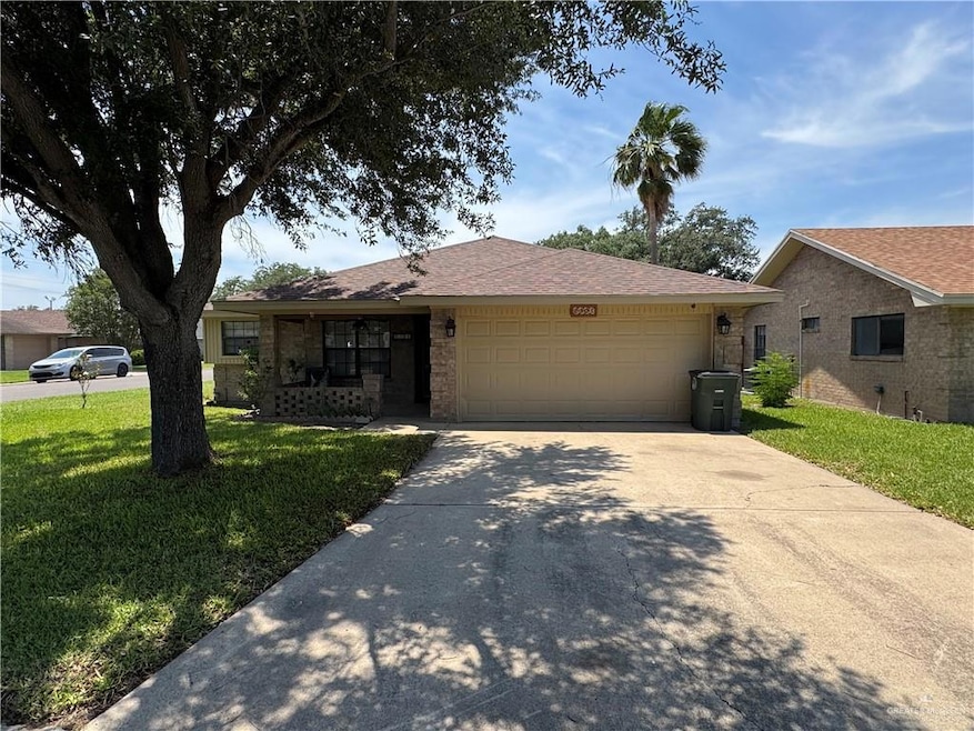 Ranch-style home featuring a garage, driveway, a front yard, and covered porch