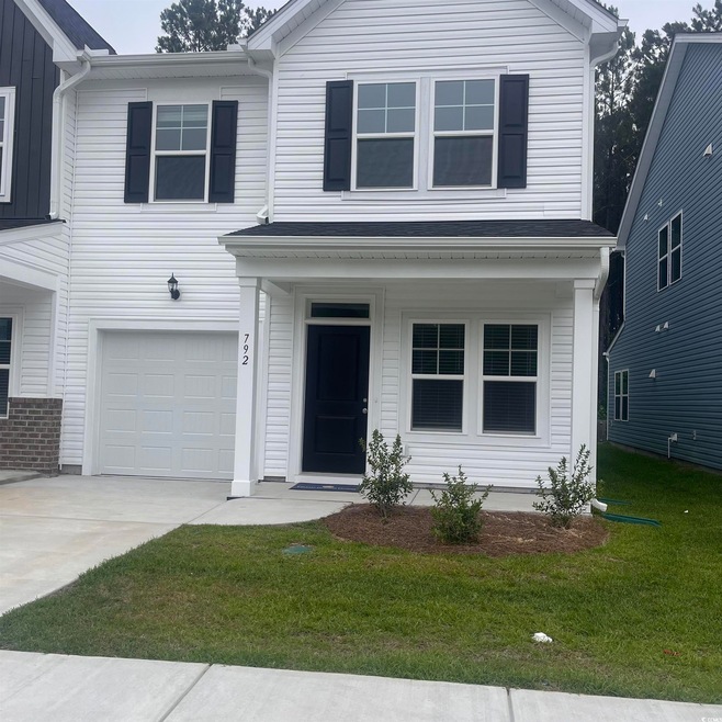 View of front of property with a garage, a front lawn, concrete driveway, and a porch