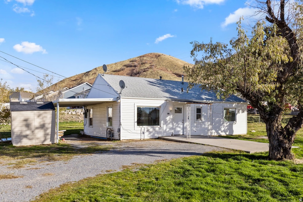View of front of house with a front yard, a mountain view, an attached carport, and a patio
