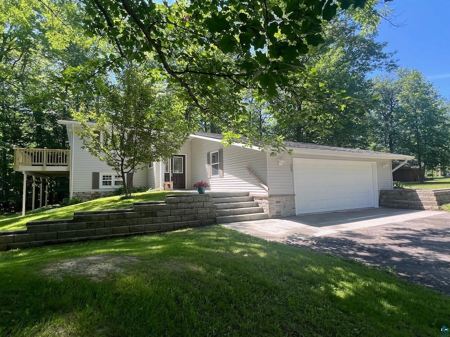 View of front facade featuring asphalt driveway, an attached garage, a front yard, and stone siding
