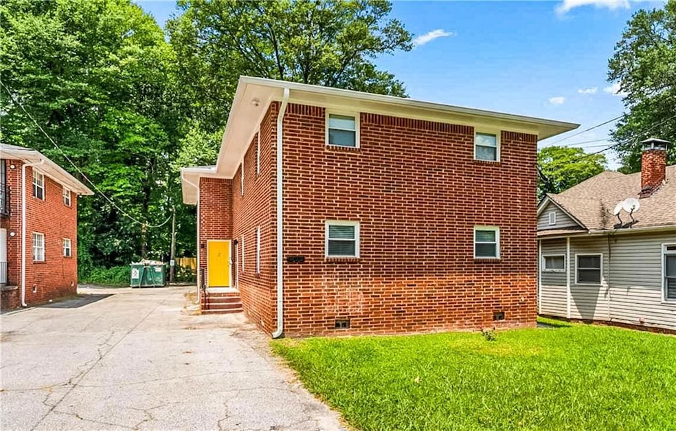 View of home's exterior featuring entry steps, brick siding, asphalt driveway, and a lawn