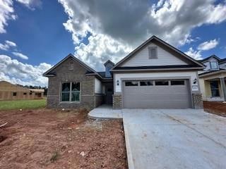 View of front of property featuring driveway, a garage, and stone siding