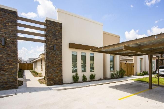 View of building exterior featuring fence and covered parking