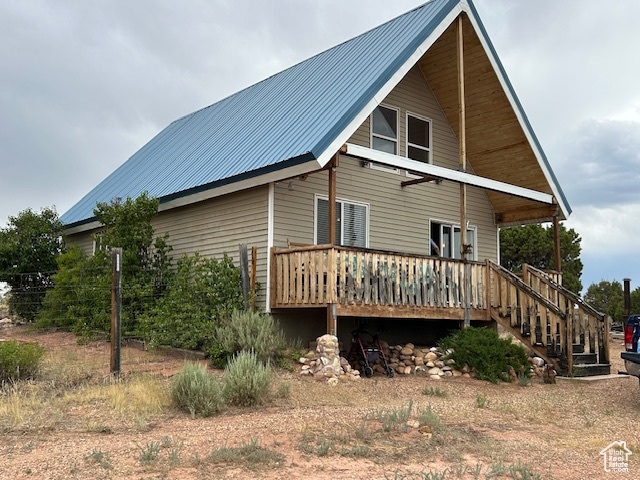 View of property exterior with a wooden deck, a metal roof, and stairway