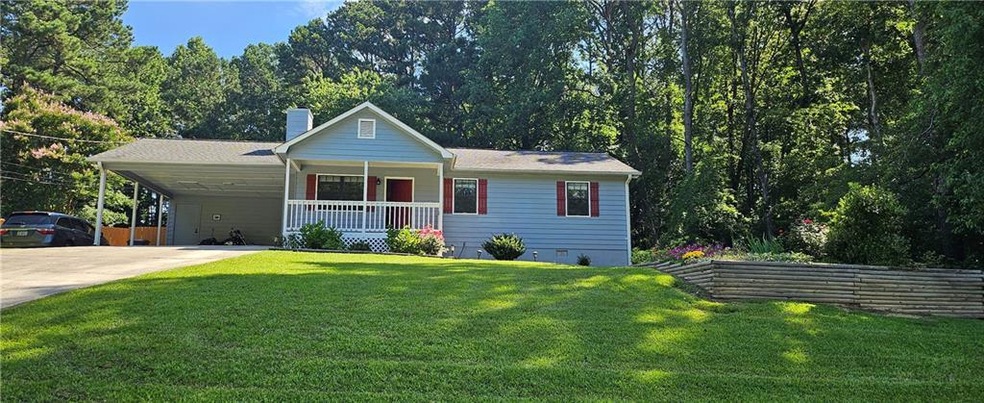 View of front facade with a porch, concrete driveway, a chimney, a front yard, and a carport