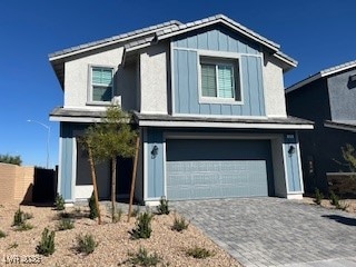 View of front of property with board and batten siding, an attached garage, and decorative driveway