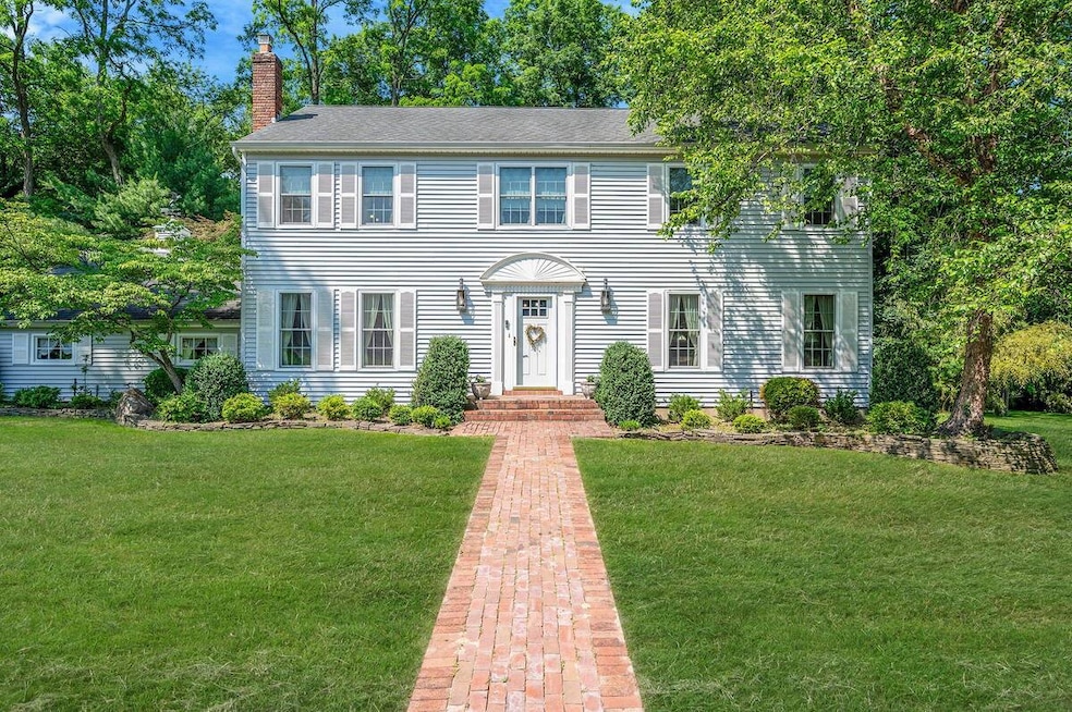 Colonial inspired home featuring a chimney and a front yard