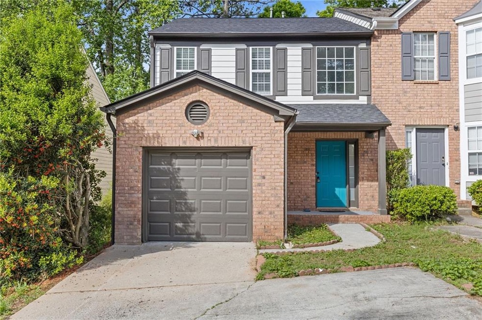 View of front of home featuring a garage, brick siding, driveway, and roof with shingles