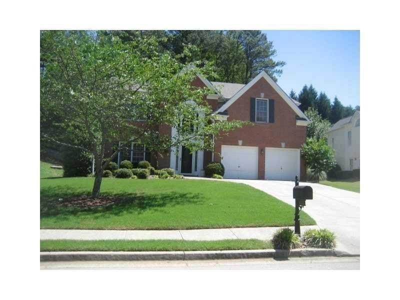 View of front of property with an attached garage, concrete driveway, and a front yard