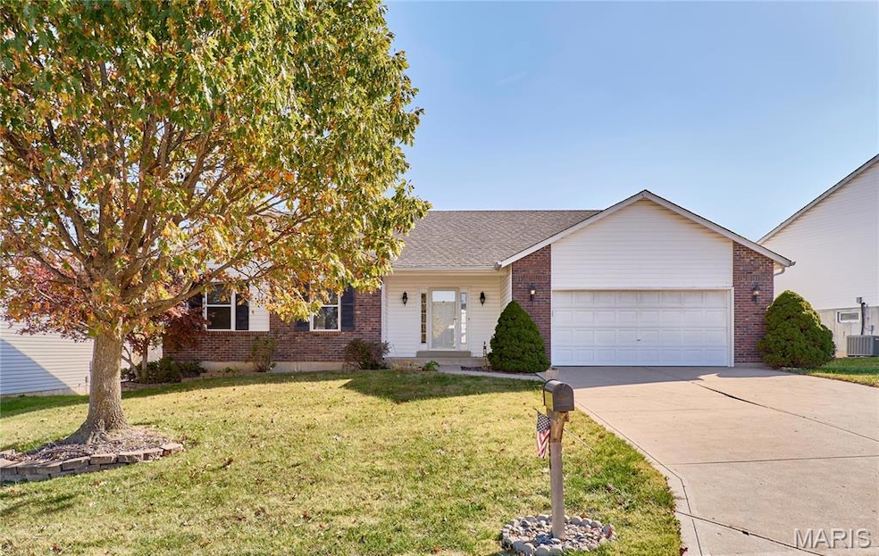 View of front of property with a front yard, driveway, brick siding, and a garage
