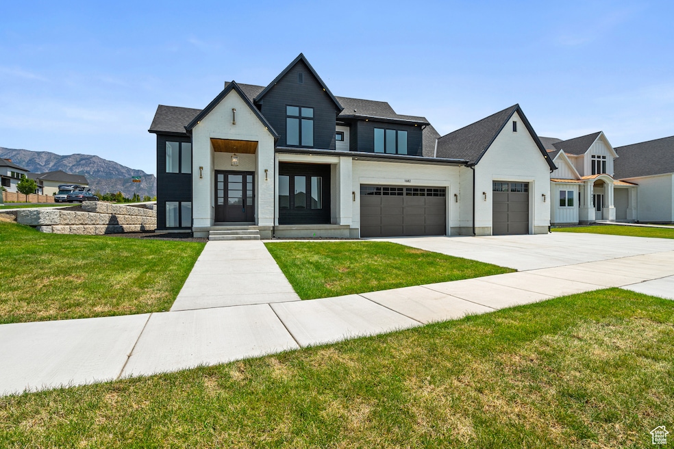 Modern farmhouse featuring concrete driveway, a garage, a front yard, roof with shingles, and a mountain view