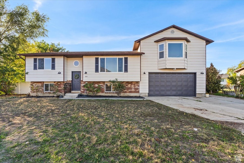Split foyer home featuring brick siding, a garage, driveway, and a front yard