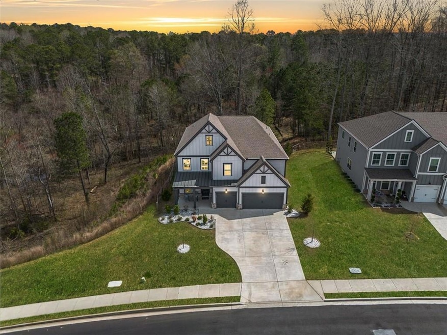 View of front of home featuring a yard, driveway, board and batten siding, and a view of trees