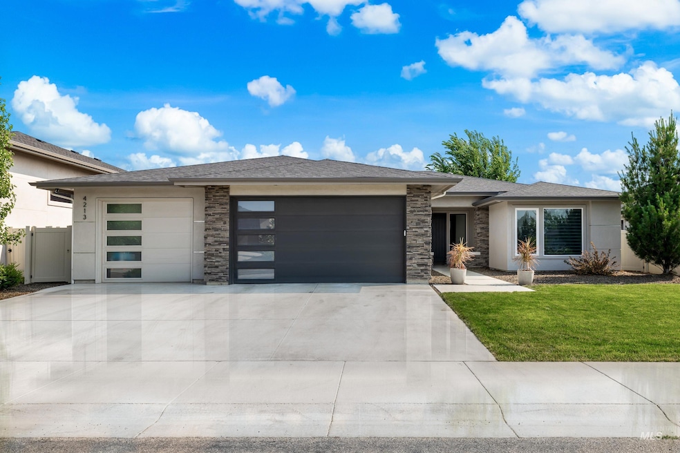 Prairie-style home with an attached garage, concrete driveway, a front lawn, and stone siding