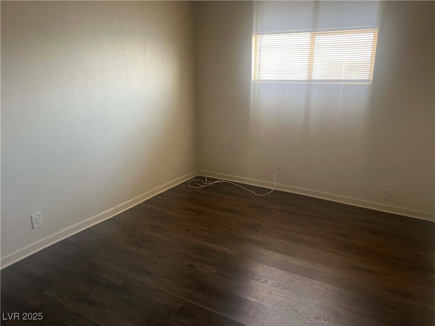 Spare room with baseboards and dark wood-style flo