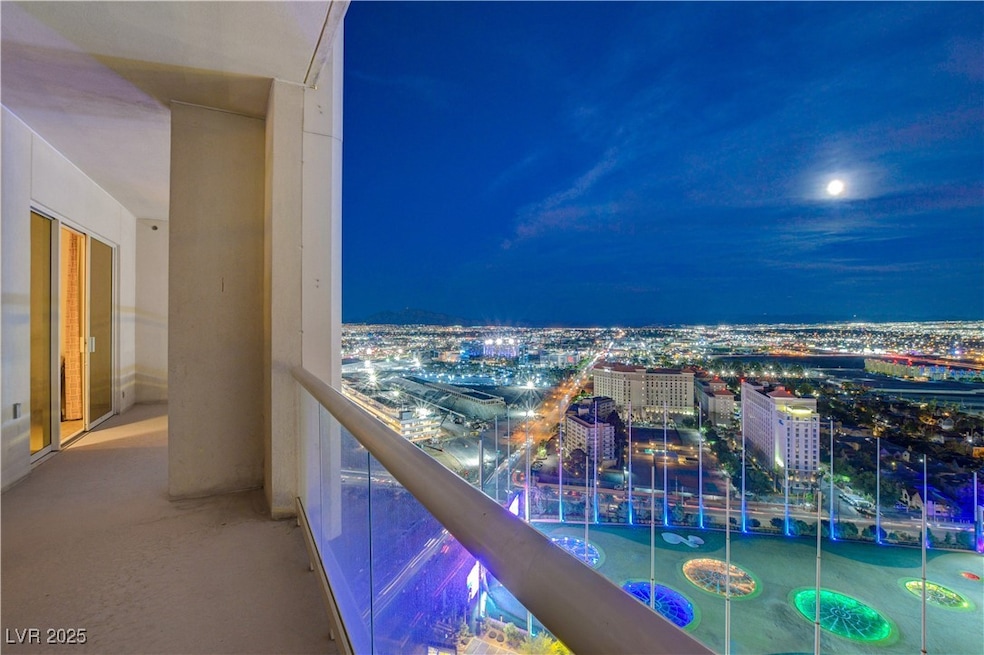 Balcony at night featuring a view of city lights