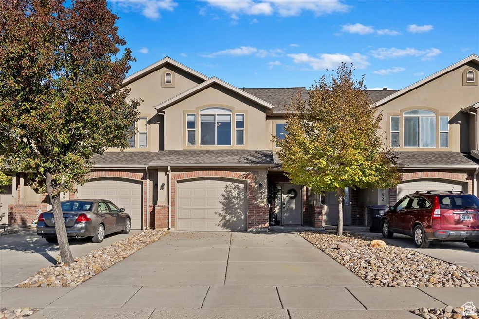 Traditional-style home featuring driveway, brick siding, an attached garage, and stucco siding