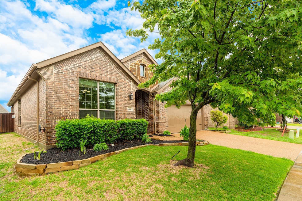 View of front facade with driveway, brick siding, and a front lawn