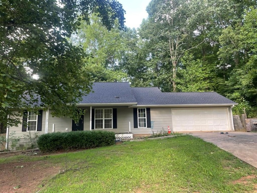 Ranch-style house featuring a front lawn and a gar