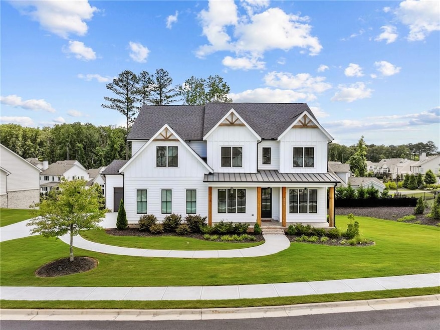 Modern farmhouse style home with board and batten siding, a front yard, covered porch, and a standing seam roof