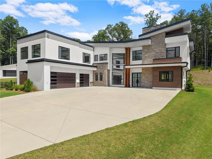 Modern home featuring stone siding, concrete driveway, a garage, a front yard, and stucco siding