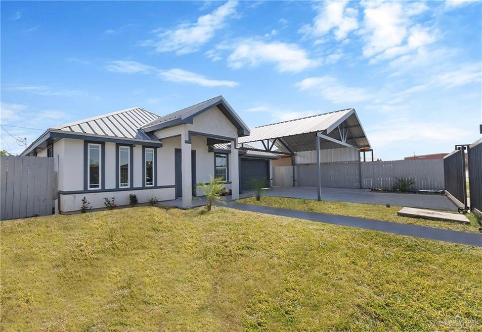 View of front of house featuring a front lawn, a carport, and a garage