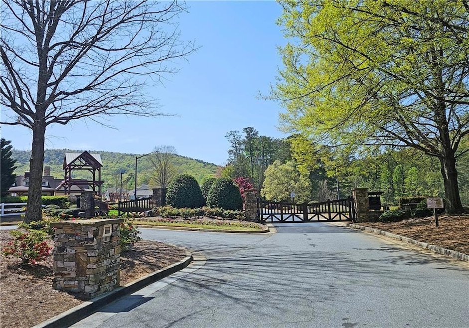 View of asphalt street featuring a gate, curbs, and a gated entry